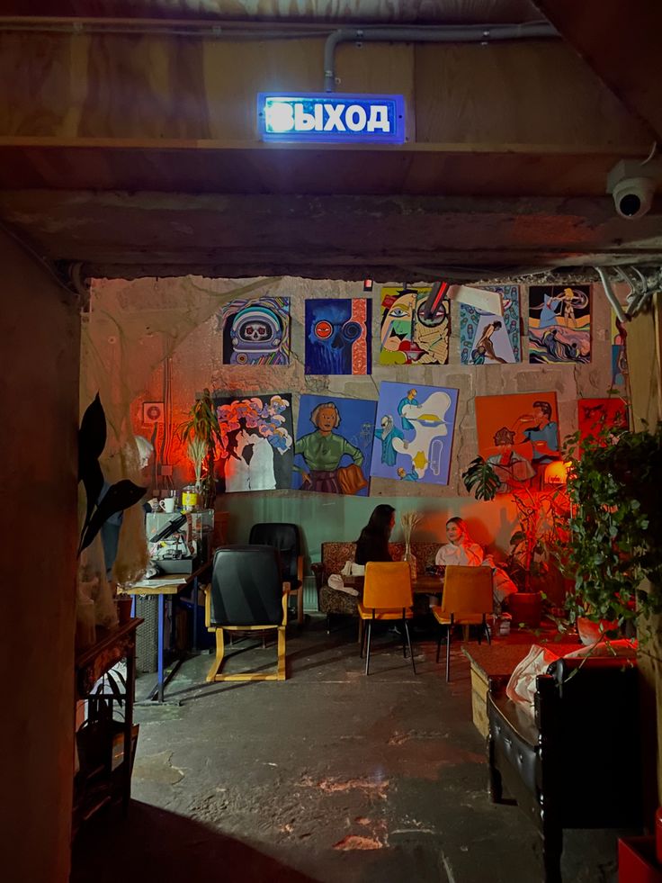 a room filled with furniture and paintings on the wall next to a neon sign that reads aoki