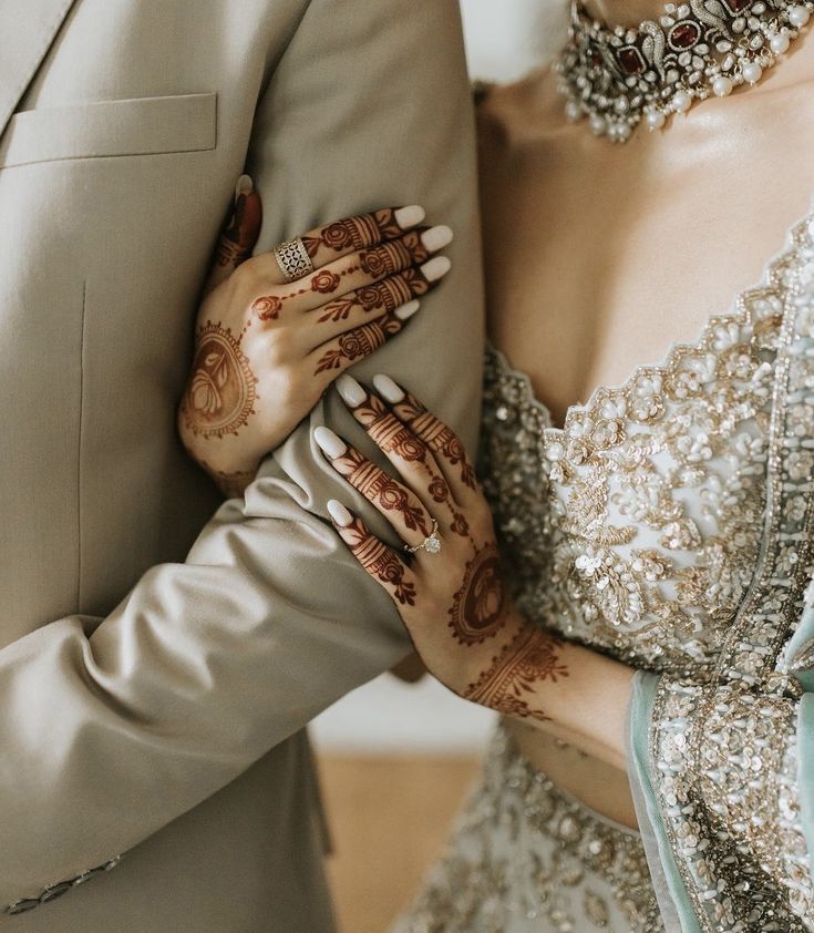 the bride and groom are holding their hands close to each other with henna tattoos on them