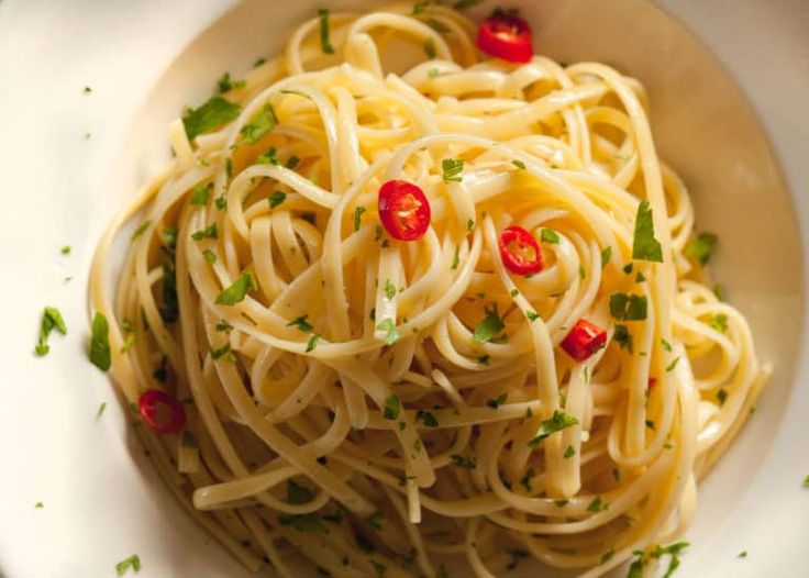 a white bowl filled with pasta and garnished with parsley