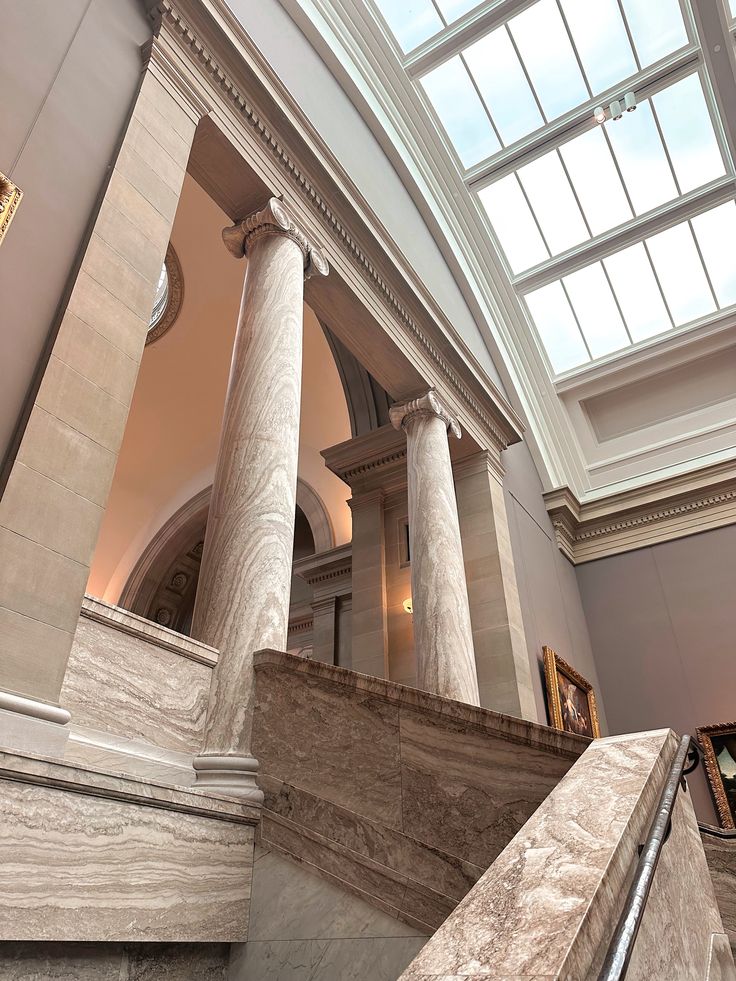 the interior of a building with marble columns and glass ceilinging, along with paintings on the walls