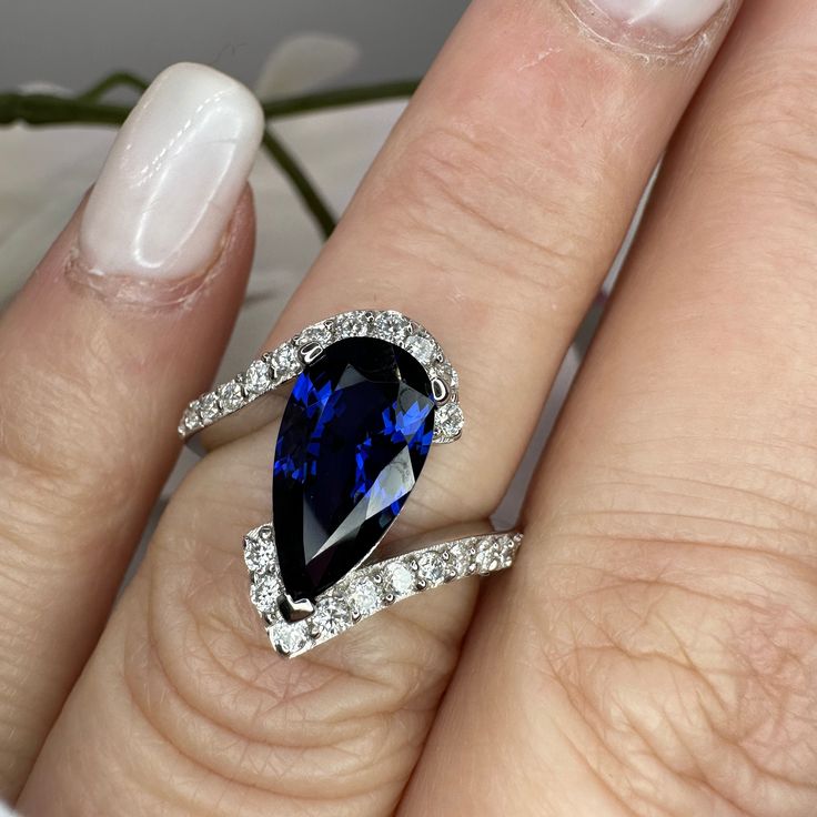 a woman's engagement ring with a blue sapphire and diamonds on the band, set in white gold