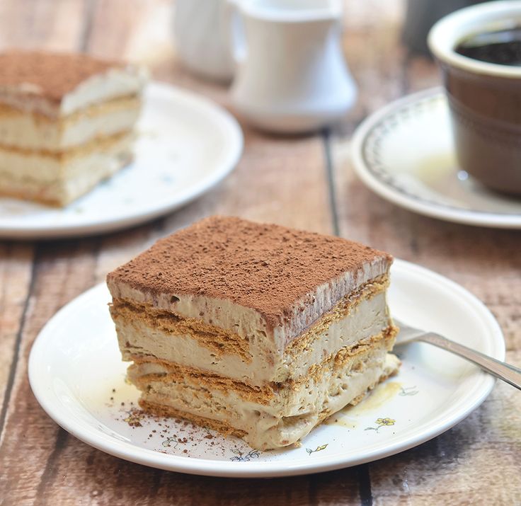 a piece of icebox cake sitting on top of a white plate next to a cup of coffee