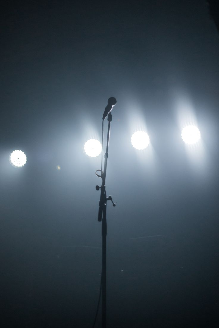 a microphone on a tripod in front of spotlights with fog and light behind it