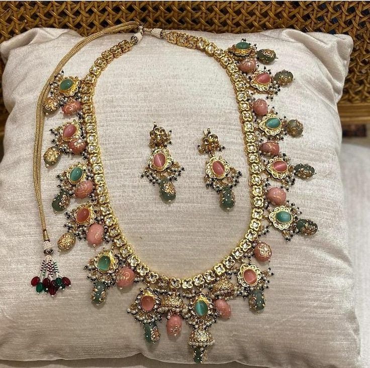 an elaborate necklace and earring set is displayed on a cushion in front of a pillow