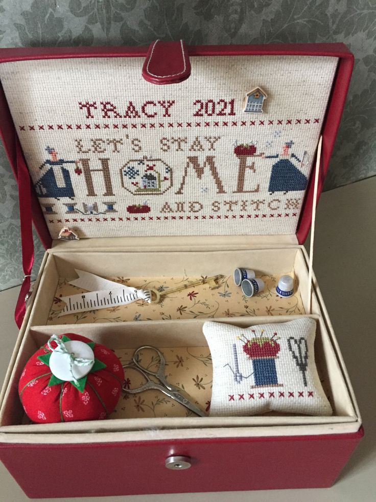 a sewing kit in a red case with needle and thread on the inside that says home