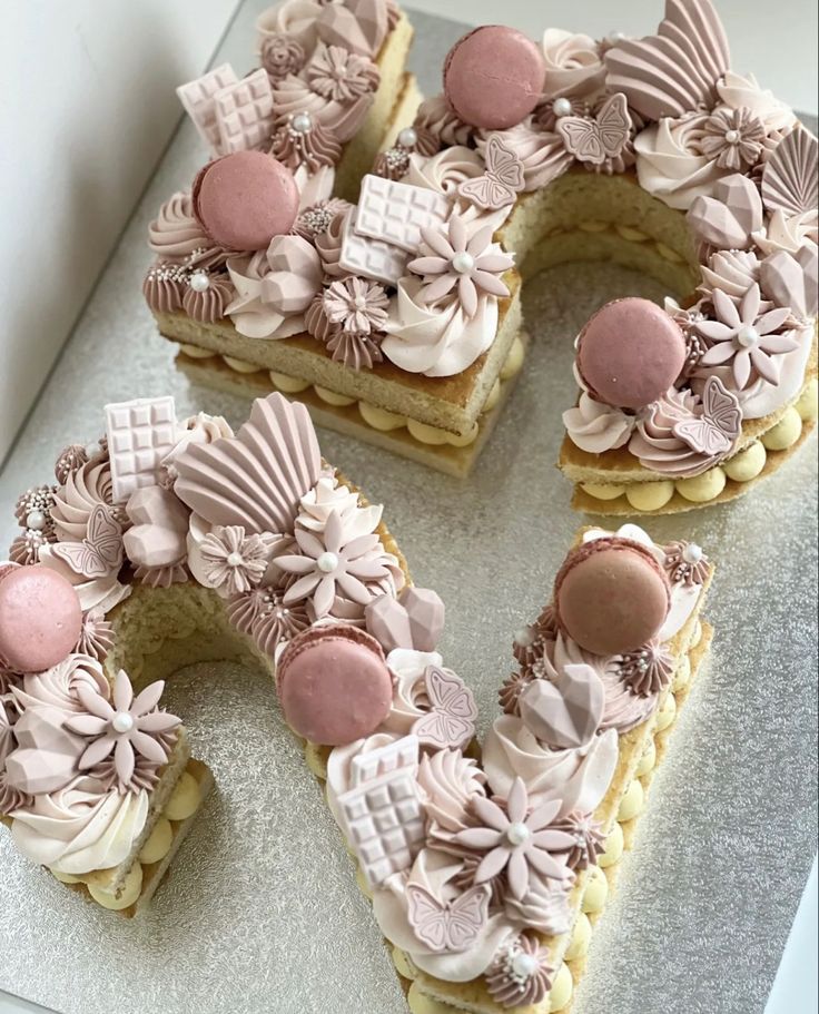 there is a letter made out of cookies and icing on the cake plate with flowers