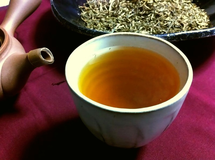 a cup of tea next to a bowl of dried herbs