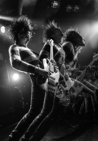 three people on stage with guitars and lights