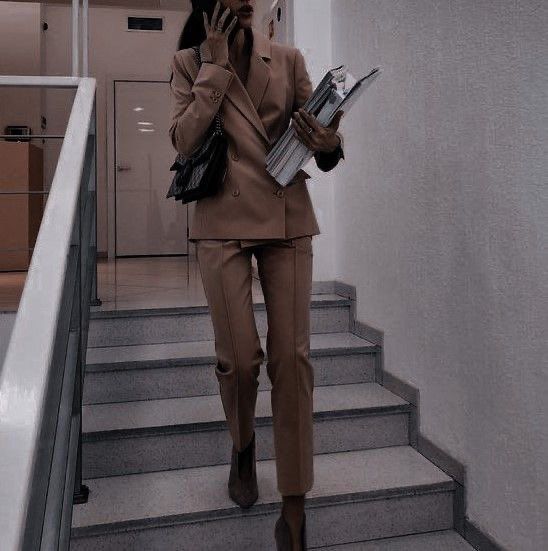 a woman is walking down the stairs talking on her cell phone and holding books in her hand