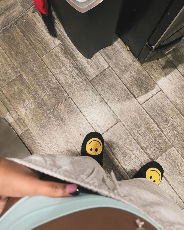 someone's feet with smiley face slippers on in the middle of a kitchen floor