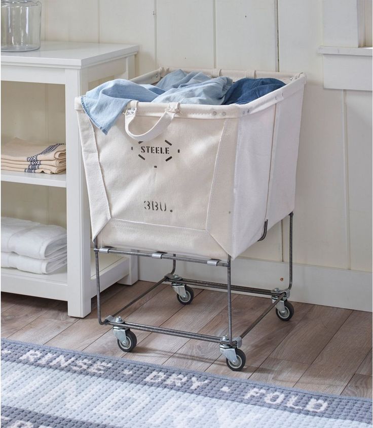 a laundry basket sitting on top of a wooden floor next to a white shelf with towels