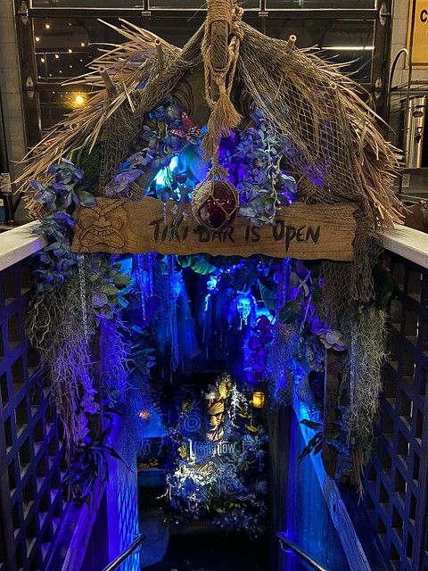 an entrance to the lost garden with blue lights and plants on it's sides