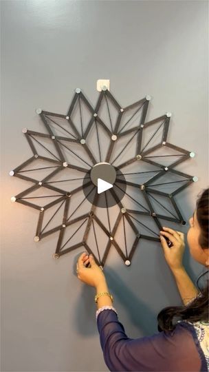 a woman is working on a wall decoration with geometric shapes and led lights in the shape of a flower