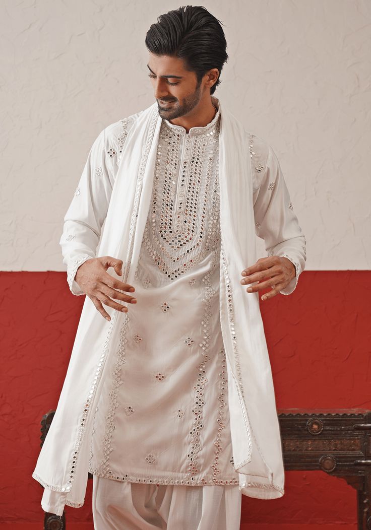 Elevate your style with White Embroidered mirror Kurta. Crafted from georgette, the classic white kurta features intricate hand embroidery and real mirror work, adding a touch of sophistication. Completed with a same-color embroidered dupatta and matching pants. Perfect for Sangeet, Mehendi, Haldi, or as a wedding guest outfit. Composition : Kurta, Patiyala & Dupatta : Viscose Georgette Care: Dry Clean Only and Vacuum Storage This product can be customized for sleeves, length and colour Delivery Unstitched Off White Kurta With Mirror Work, Wedding Cotton Sherwani With Mirror Work, Off White Kurta With Mirror Work For Eid, Off White Mirror Work Kurta For Eid, Cotton Sherwani With Mirror Work For Wedding, Designer White Sherwani With Mirror Work, Designer Off White Kurta With Mirror Work, Off White Mirror Work Kurta For Designer Wear, Festive Off White Kurta With Mirror Work