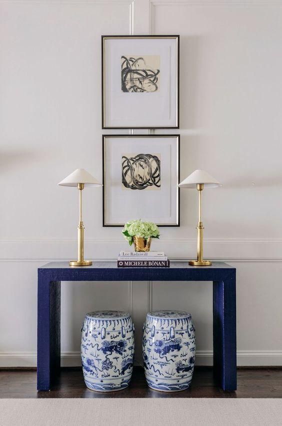 a blue and white table with two vases next to it on the sideboard