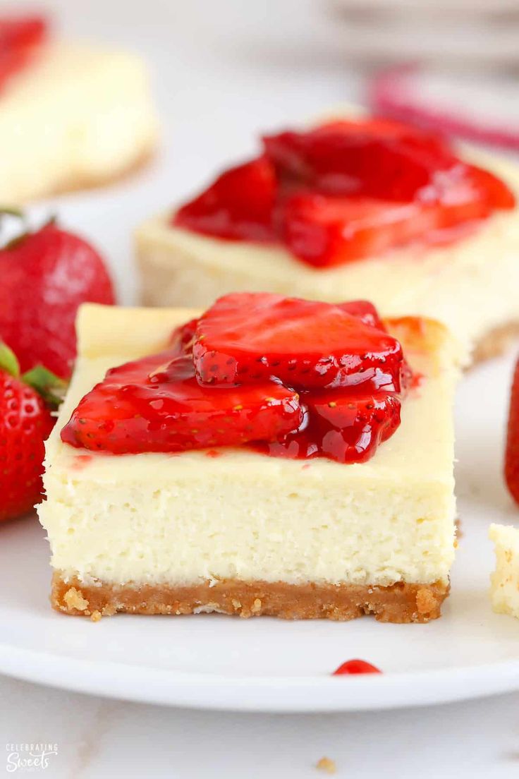 two slices of cheesecake with strawberry toppings on a plate next to strawberries