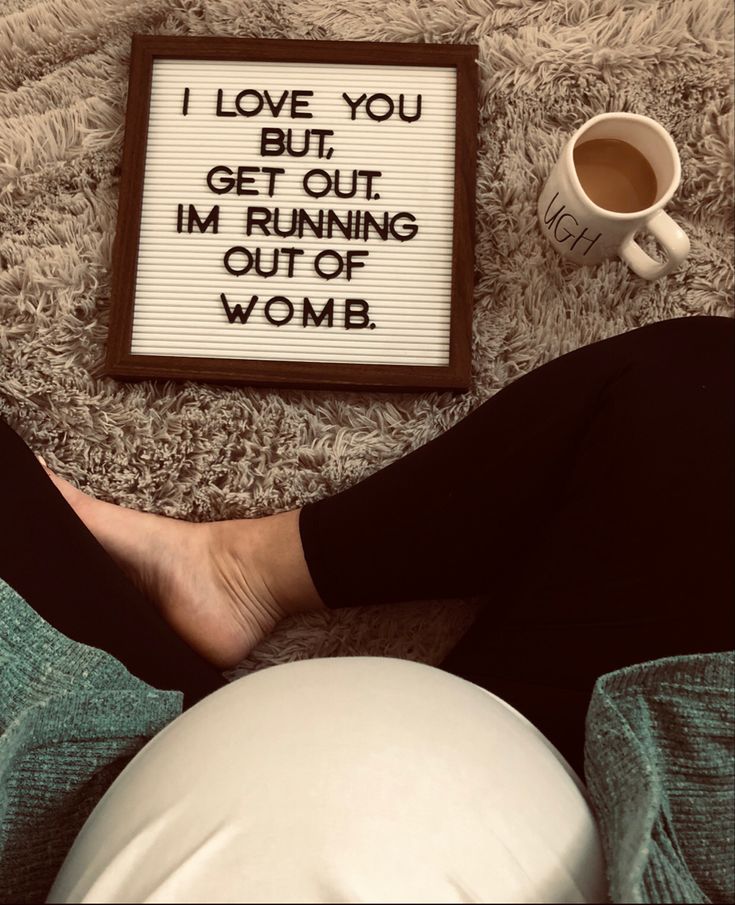 a woman's feet resting next to a sign that says i love you, but get out im running out of womb