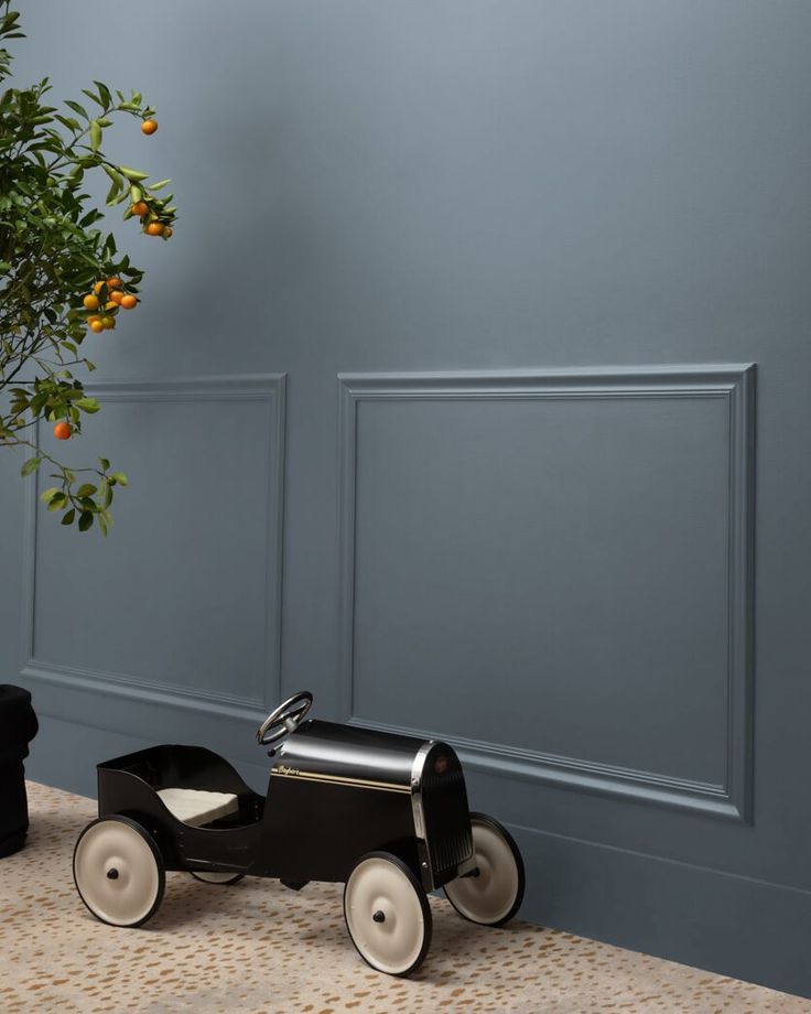 a black toy car sitting next to a potted plant