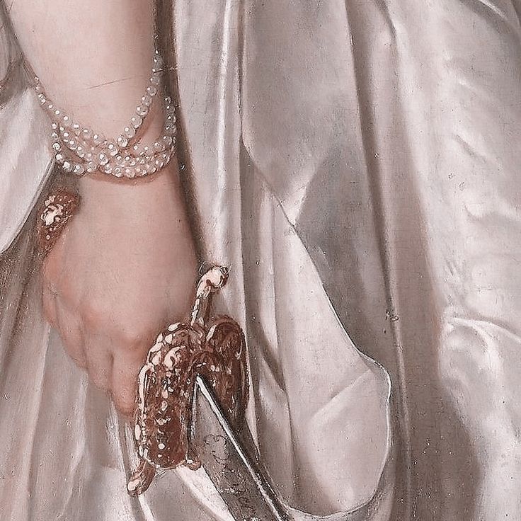 a woman in a silver dress holding onto a pair of shoes with pearls on them