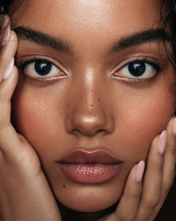 a close up of a woman's face with her hands on her head and one hand near her face