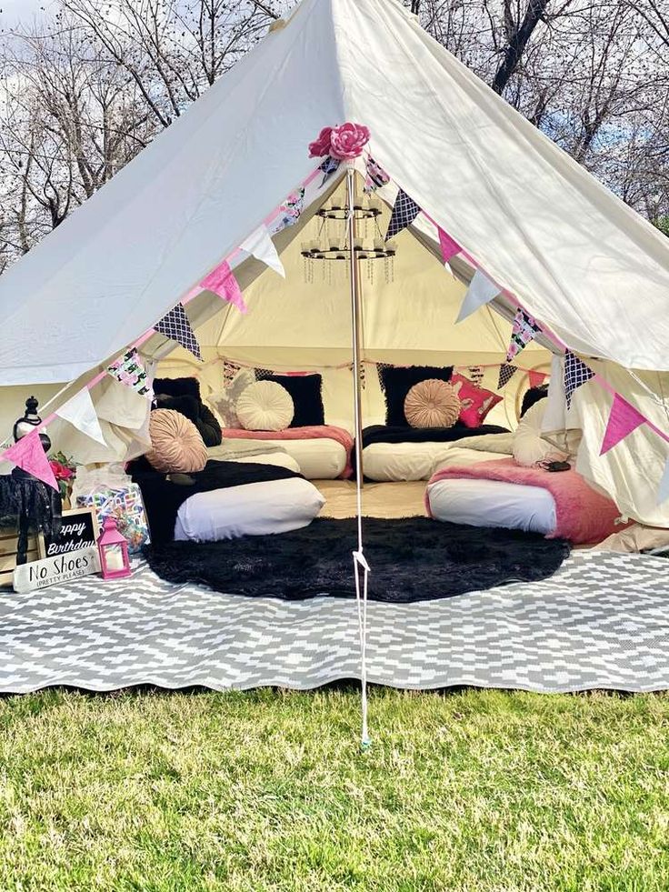 a white tent with pink and black decorations on it in the middle of a field