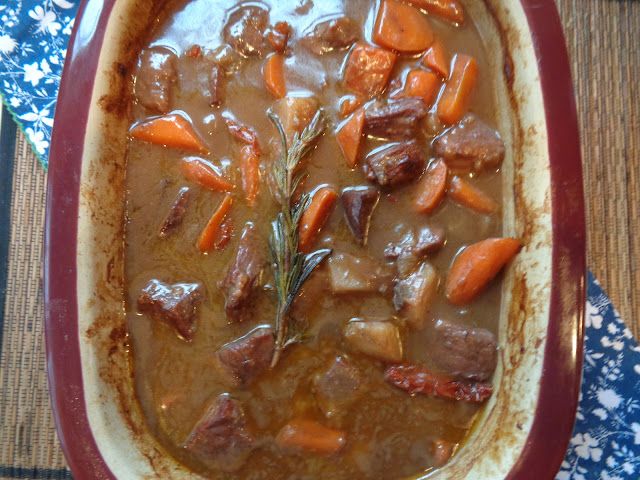 a bowl filled with stew and carrots on top of a table