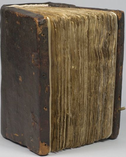 an old book sitting on top of a white table next to a black and brown object