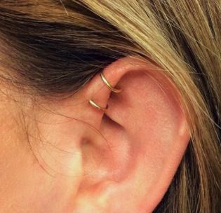 a woman's ear is shown with two small gold rings on the side of her ear