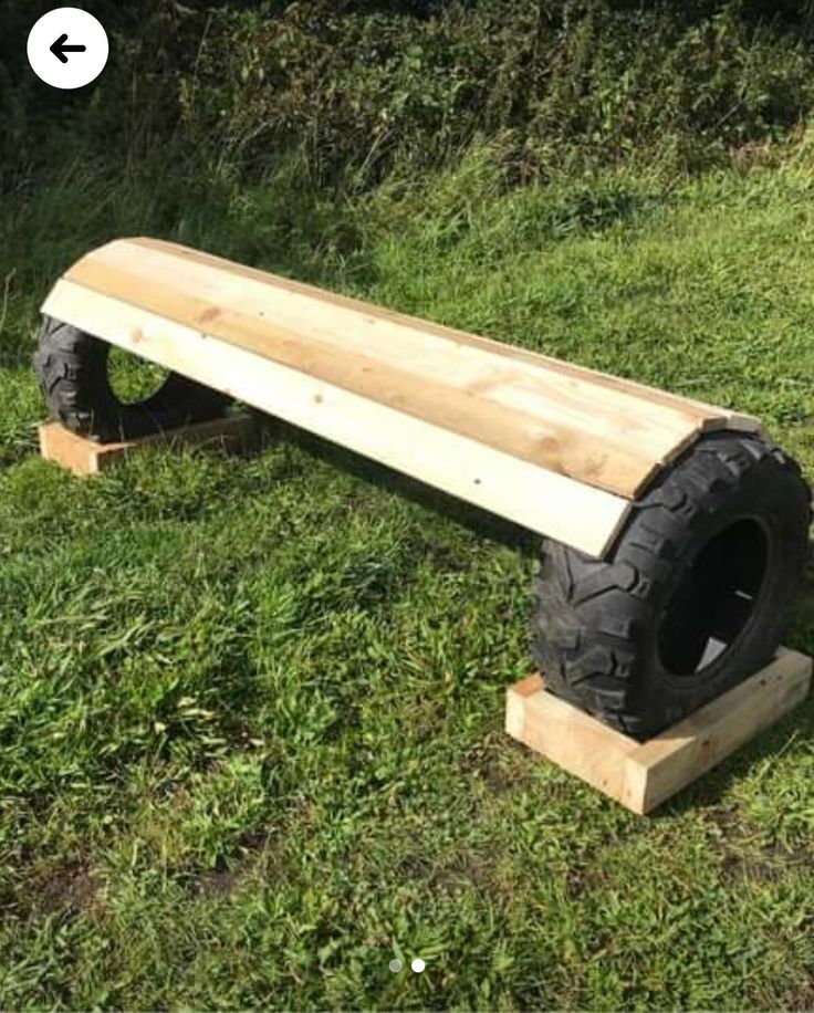 a bench made out of an old tire is sitting in the middle of some grass