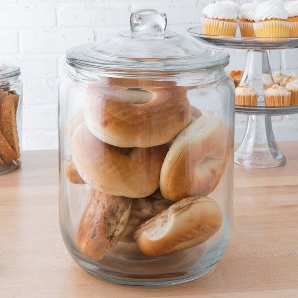 a glass jar filled with lots of doughnuts on top of a wooden table