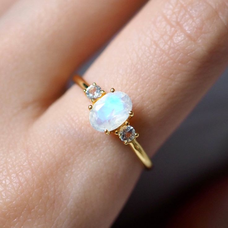 14k Solid Yellow Gold Engagement Ring / Handmade Jewelry Rainbow Moonstone White Topaz Gemstone Ring Wedding Gift Ring Minimalist Dainty Ring ✦ Description ✦  * 14k & 18k Solid Gold With Stamped  * Gemstone : Natural Rainbow Moonstone  * Moonstone Size : 7x5 mm * Side Stone : Natural White Topaz  * Topaz Size : 2.5 mm * 14K Solid Yellow Gold, ( Available in 14K & 18K Yellow, Rose, and White Gold ) * Option available in 18K Gold * All size available * Ready to Ship in 1-2 Weeks ≫ FAQ below for more detail. ✦ Sizing We can adjust most items to fit your sizing preferences. Most items can be made to any size and length. Please leave a note at checkout or contact us via Etsy conversation. Even after purchasing the item, you can still ask us to adjust the size or length. We will try our best to Dainty Oval Moonstone Promise Ring, White Moonstone Promise Ring In 14k Gold, White 14k Gold Moonstone Promise Ring, White Moonstone Ring In 14k Gold For Promise, 14k Gold Moonstone Promise Ring With Accent Stones, 14k Gold Moonstone Ring With Gemstone Accents, Gold Moonstone Ring With Gemstone Accents For Anniversary, Moonstone Rings With Rose Cut Diamonds, 14k Gold Moonstone Ring With Accent Stones For Anniversary