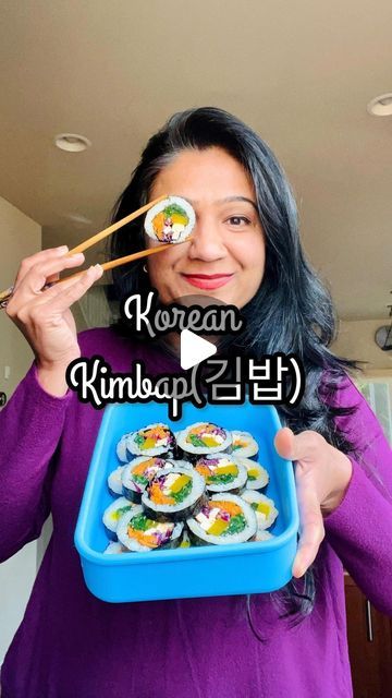 a woman holding a tray of sushi and chopsticks