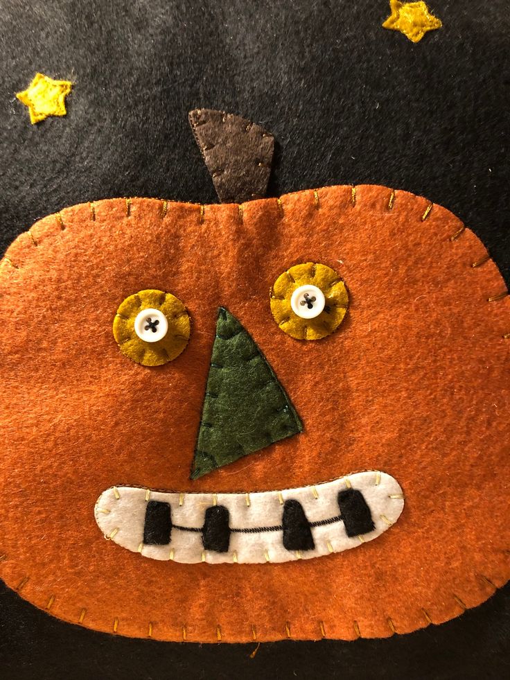 a close up of a felt pumpkin face