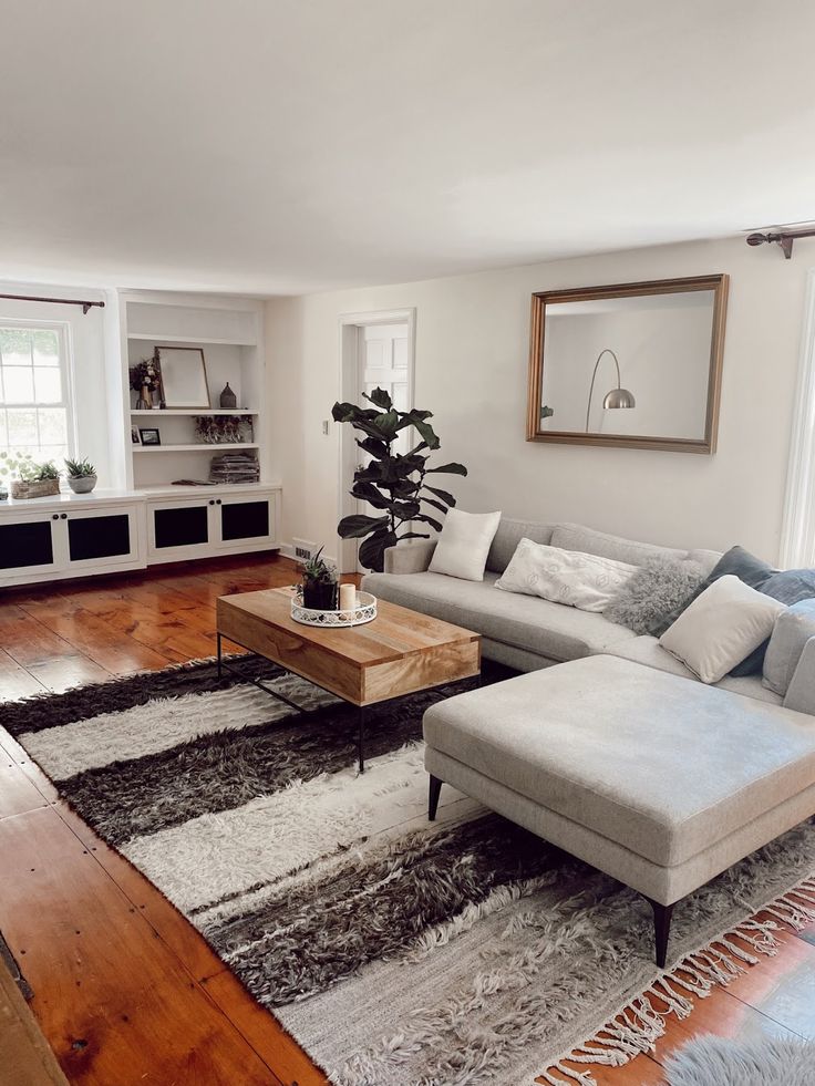 a living room filled with furniture and a large rug on top of a hard wood floor