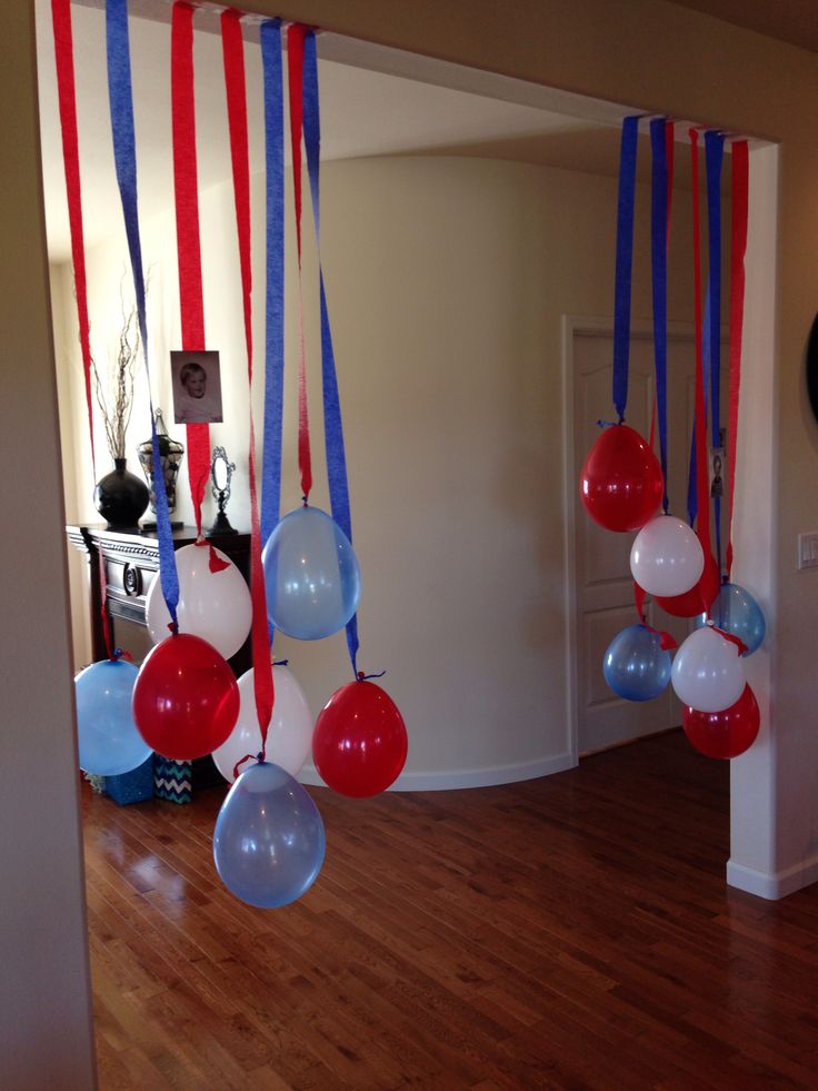 red, white and blue balloons are hanging from the ceiling