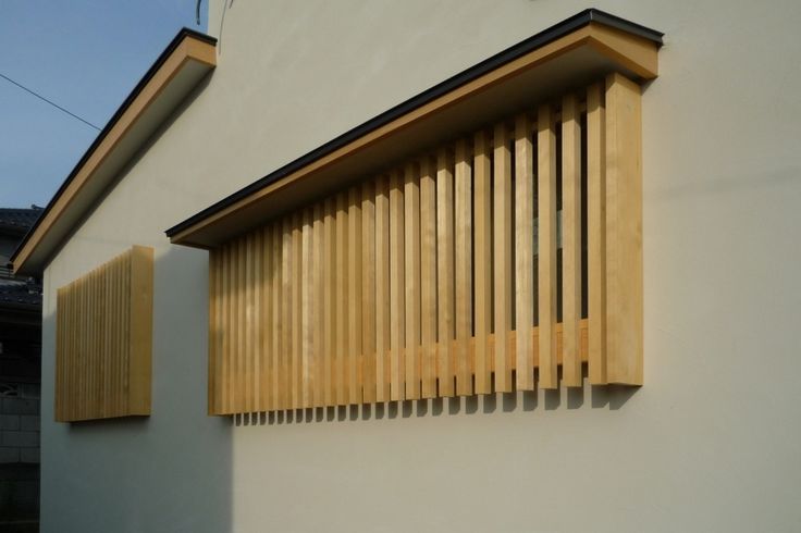 a wooden window on the side of a white building with vertical slatted shutters