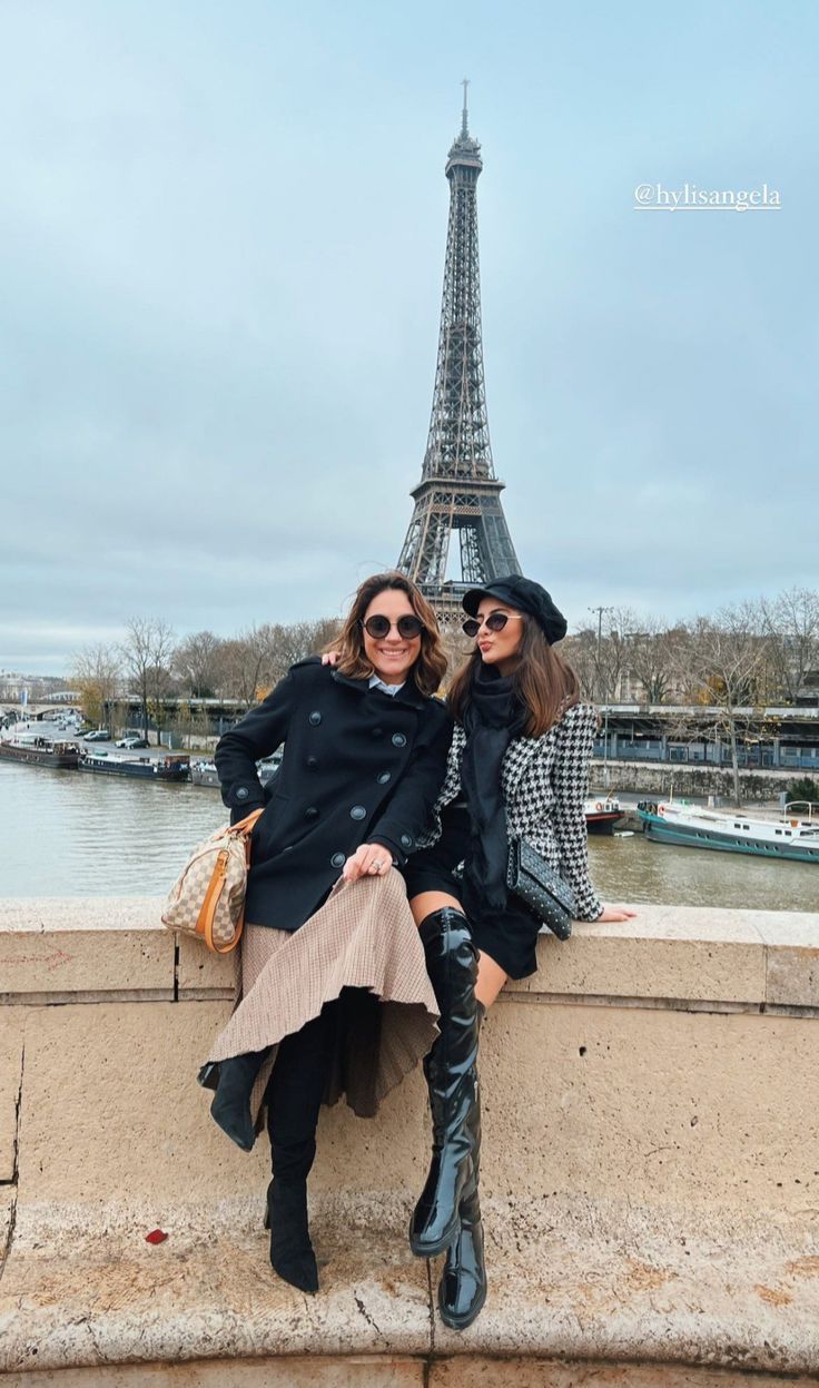 two women sitting next to each other in front of the eiffel tower