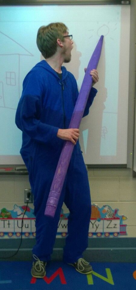 a man holding a giant purple object in front of a whiteboard