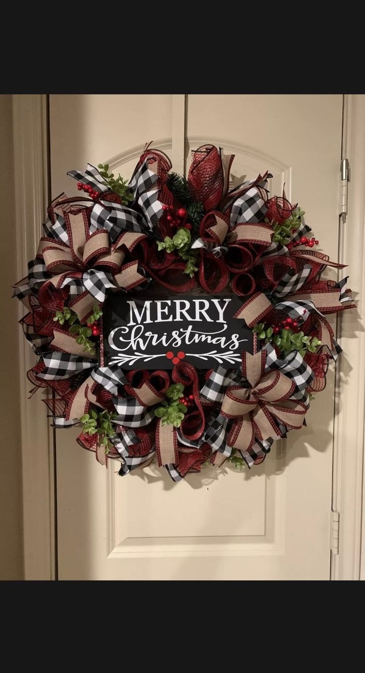 a merry christmas wreath hanging on the front door with ribbon and bow around it's edges