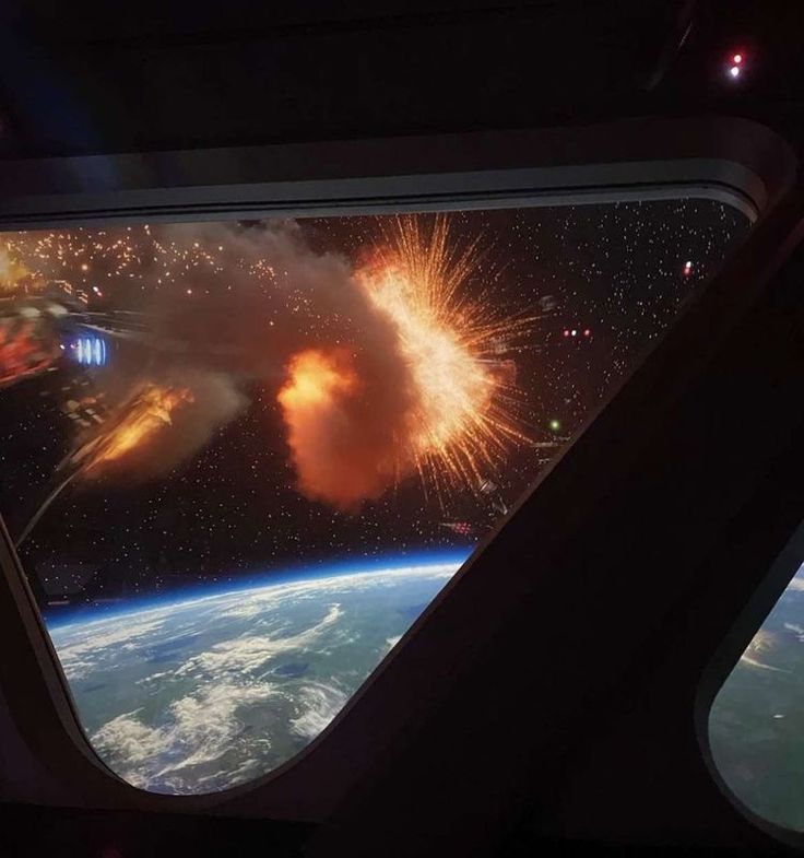 the view from an airplane window shows fireworks and earth's horizon as seen from space