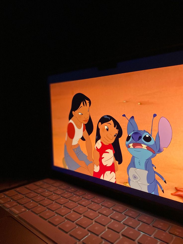 a laptop computer sitting on top of a table with cartoon characters on the screen in front of it