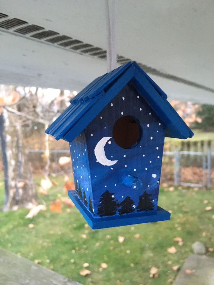 a blue birdhouse hanging from the side of a house with a moon and stars painted on it