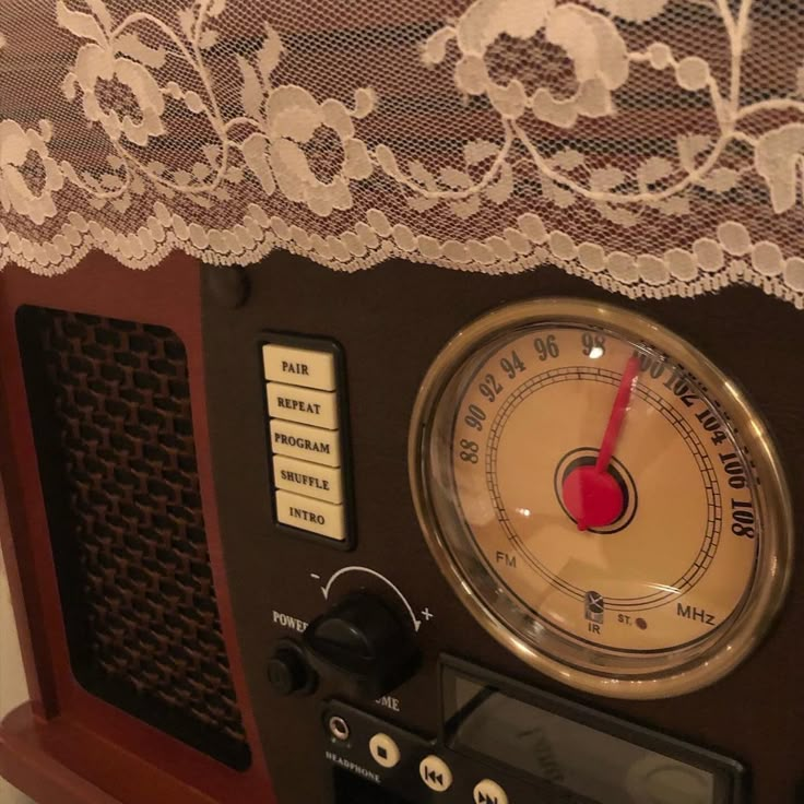 an old fashioned radio sitting on top of a wooden table next to a lace curtain