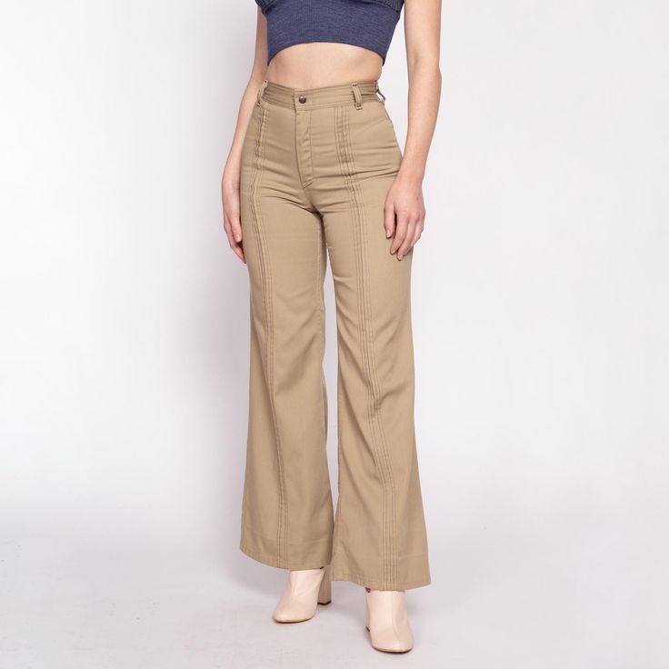 Vintage 70s women's khaki high waist trousers with a flared leg, brown contrast stitching and pleating down the fronts of the legs, and a saddleback cut in the back. They have been taken in about 1/2" at each side of waist, which could be let out if desired. Measurements and Condition: Fits like: Small (see measurements to ensure fit) Fabric: Feels like polyester Brand: March Condition: Very good, with light general wear, and two tiny brown spots on the inner left leg. Waist: 25.5" Hips: 37" - taken at the bottom of the zipper opening Rise: 11.25"  Inseam: 31" Shown on a 5'8" model with measurements of 34"-26"-37", usually wears a size small. See our FAQ for more info on sizing and condition ratings. High Waisted Bell Bottoms, Retro Trousers, 70s Women, Womens Khakis, High Waisted Trousers, Flare Pants, Bell Bottoms, Trousers Women, Capri Pants