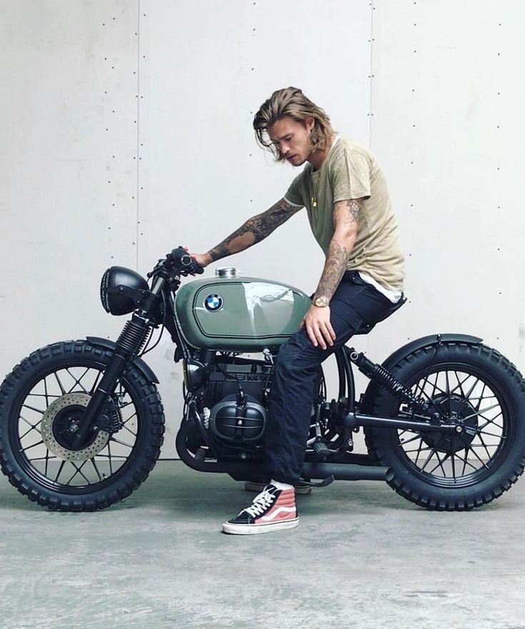 a man sitting on top of a motorcycle with his foot on the seat and looking down