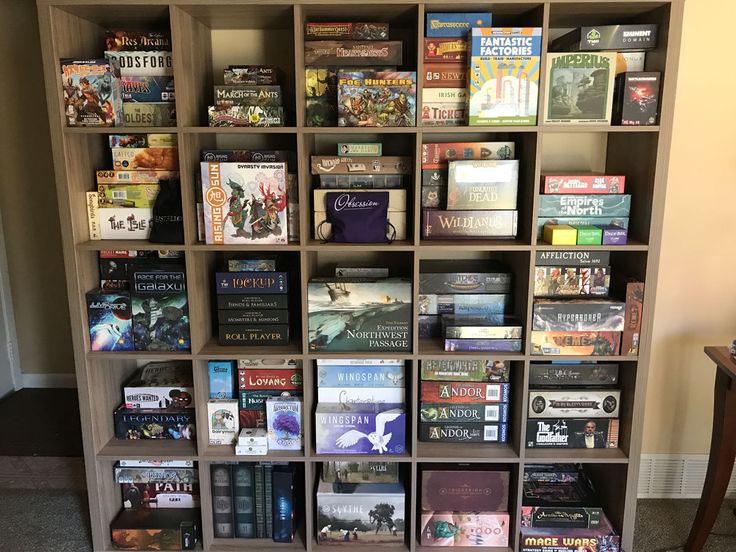 a book shelf filled with lots of books on top of carpeted floor next to a wall