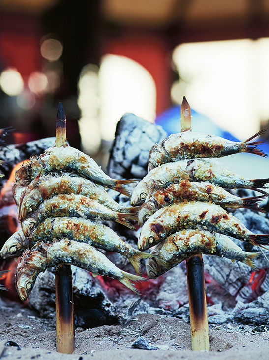 some kind of food on sticks in the sand