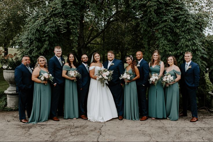 a group of people standing next to each other in front of some trees and bushes