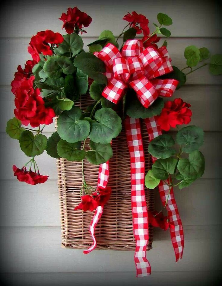 a basket filled with red flowers sitting on top of a wall