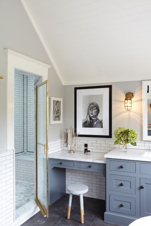 a bathroom with blue cabinets and white counter tops, framed pictures on the wall above it